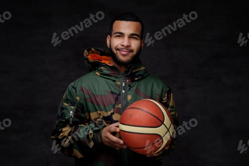 Preview: Happy young African-American street basketball player in a camouflage jacket.