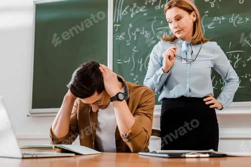 Preview: Student holding head and looking upset near female teacher