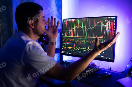 Preview: Confused shocked programmer sits at home office in front of computer screen with graphs of