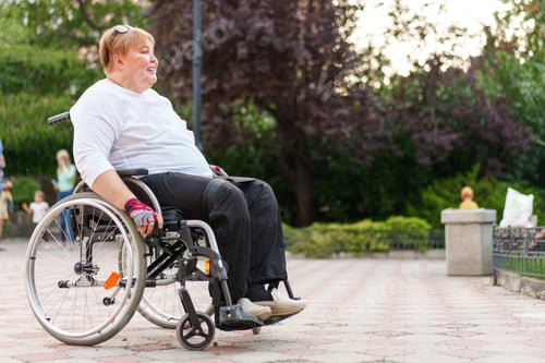 Preview: Mature woman with disability sitting in wheelchair outdoors