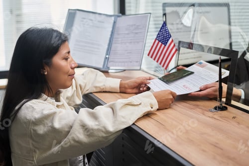 Preview: Young Adult Hispanic Woman Receiving Stamped Passport at Visa Center Counter
