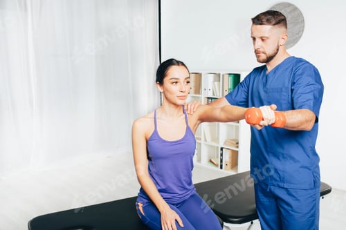 Preview: Physiotherapist working with male patient in clinic. Raises dumbbells, strengthening arm muscles