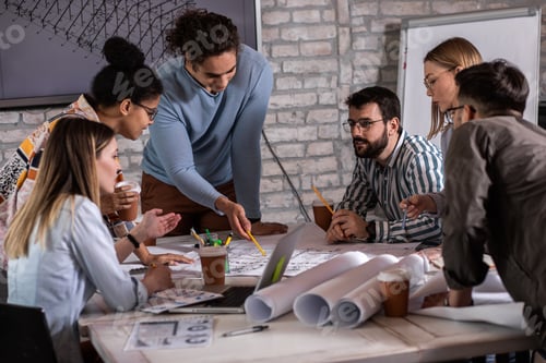 Preview: Group of modern business people in casual wear discussing architectural designs.