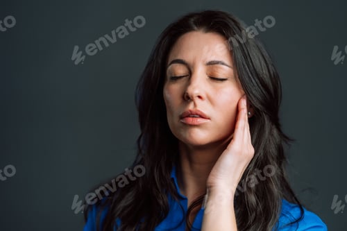 Preview: Bored mature woman with long hair having headache, studio portrait. Girl putting hands on head