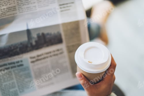 Preview: Closeup image of a woman reading newspaper and drinking coffee in the morning