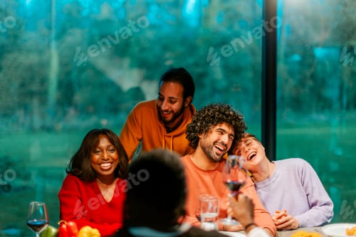 Preview: Happy friends laughing and raising a toast during a dinner party