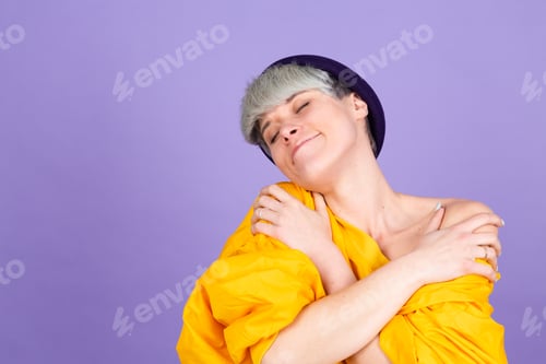 Preview: Stylish european woman on purple background self care hugging herself with smile and closed eyes