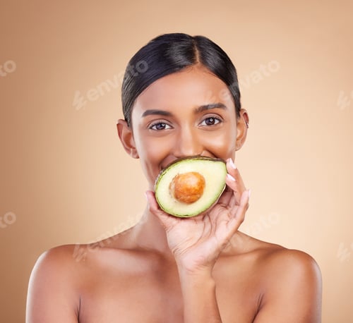 Preview: Portrait, skin or avocado with a model woman in studio on a beige background to promote beauty. Fac