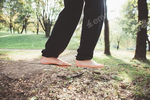 Preview: Close up unidentifiable human feet slacklining outdoors