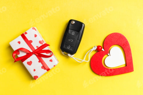Preview: Top view of gift box, car key and wooden heart on colorful background.