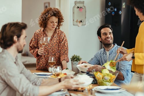 Preview: Group of young happy people enjoying in lunch time at dining table.