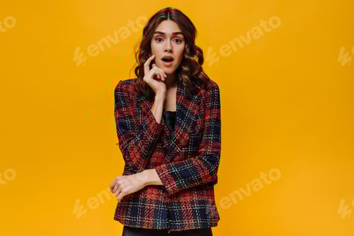 Preview: Surprised lady in red striped jacket looking into camera on isolated backdrop. Young girl with wavy