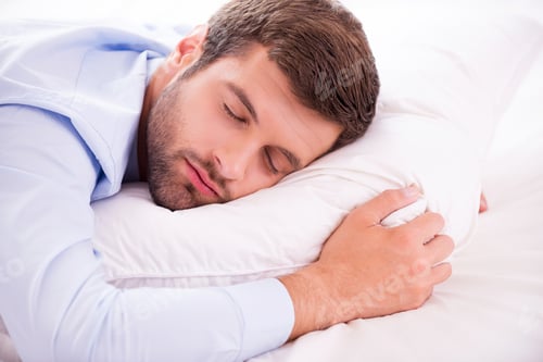 Preview: Relaxing after hard working day. Handsome young man in shirt and tie sleeping in bed