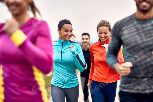 Preview: Happy athletic women having fun while jogging with group of people in nature.