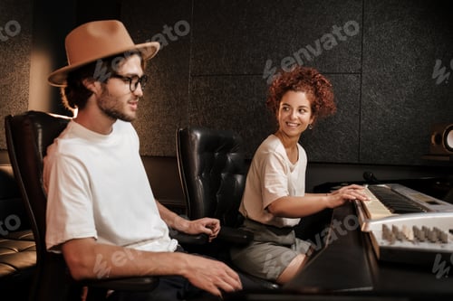 Preview: Young music band composing song on piano keyboard in modern sound recording studio