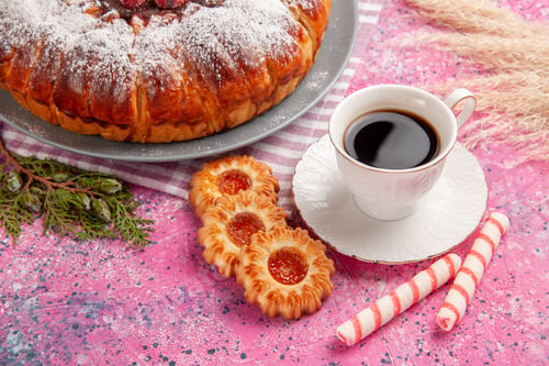 Preview: front view delicious strawberry cake sugar powdered with cup of tea and cookies on light-pink