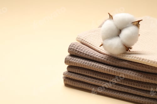 Preview: Clean waffle towels and cotton flower on beige background, closeup. Space for text