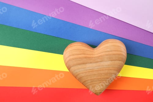 Preview: Wooden heart on rainbow background, top view. Gay symbol