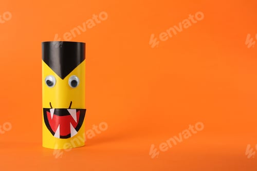 Preview: Funny yellow monster on orange background, space for text. Halloween decoration