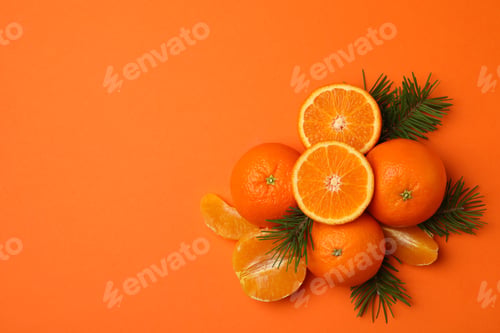 Preview: Ripe mandarins and pine branches on orange background, top view