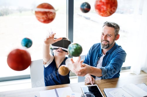 Preview: Mature father with small son and VR goggles indoors, working on school project