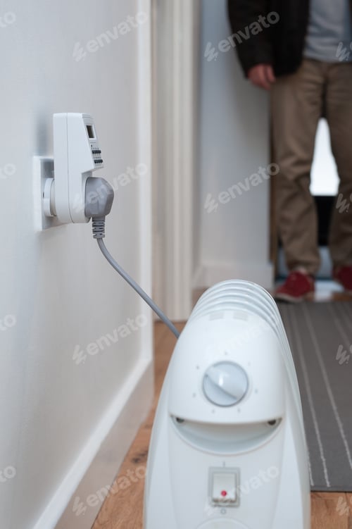 Preview: Little oil filled radiator plugged into timer device in hallway of a home. Supplemental heating.