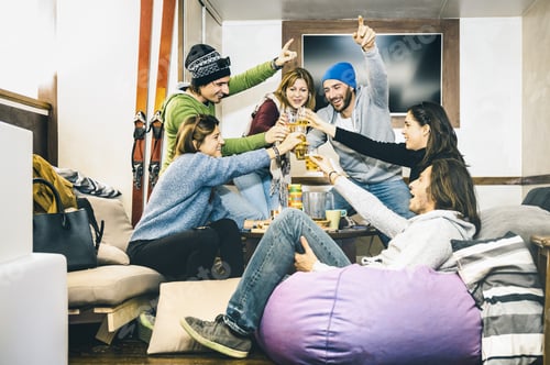Preview: Happy friends toasting and drinking beer at after ski pub lodge