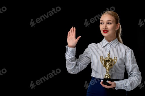 Preview: Business woman blonde cute girl holding trophy and raising hand with red lipstick in office outfit