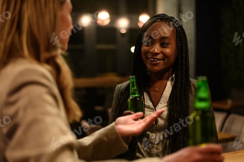 Preview: Cheerful colleagues drinking beer in the bar together after work