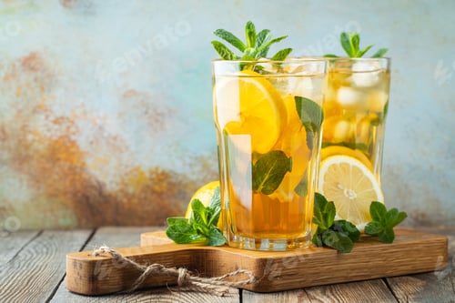 Preview: Traditional iced tea with lemon and ice in tall glasses on a wooden rustic table. With copy space