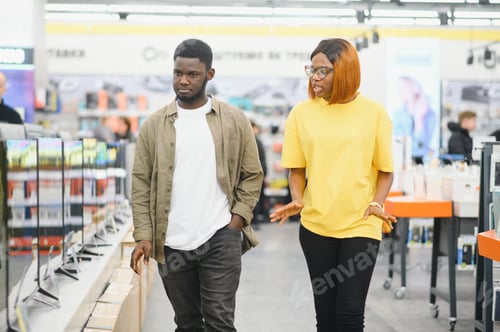 Preview: Beautiful couple buying consumer tech products in modern home appliances store.