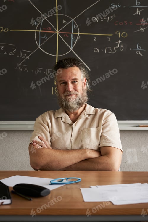 Preview: Vertical photo. Cheerful teacher looks at the camera with his arms crossed. Mathematics class.