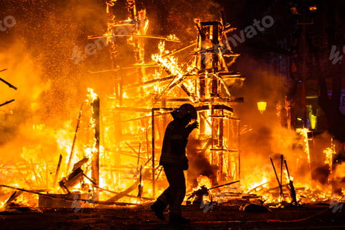 Preview: Silhouette of fireman trying to control a fire in a street during a night.