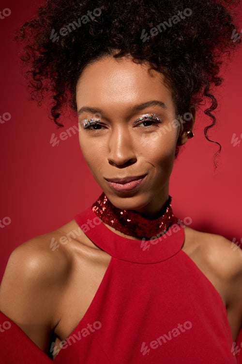 Preview: Captivating young woman radiates confidence against a vibrant red backdrop