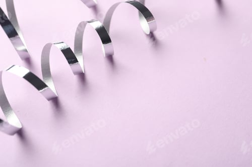 Preview: Shiny serpentine streamers on lilac background, closeup. Space for text