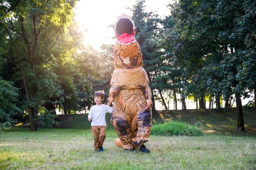 Preview: Father and son playing at the park, with a dinosaur costume, having fun with the family outdoor