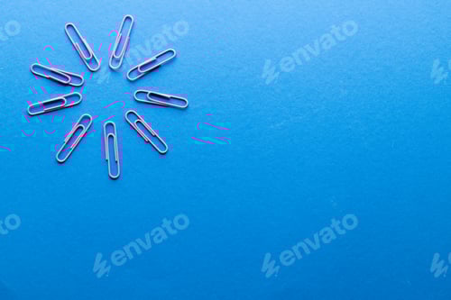 Preview: Close up of pink paper clips in circle and copy space on blue background