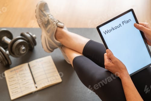 Preview: Woman preparing workout plan using digital tablet at home