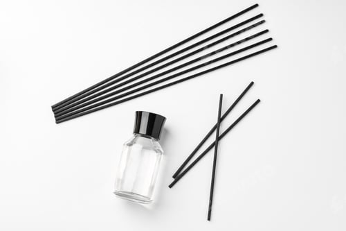 Preview: A minimalist display of essential oil and black diffuser sticks on a clean white background
