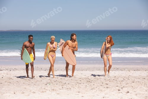 Preview: Front view of group of diverse friends walking with surfboard on the beach