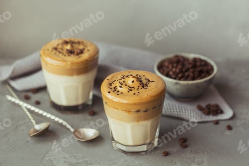 Preview: Glass of Iced Dalgona Coffee, trendy fluffy creamy whipped coffee and milk on grey background.