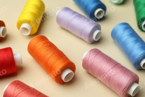Preview: Different colorful sewing threads on beige background