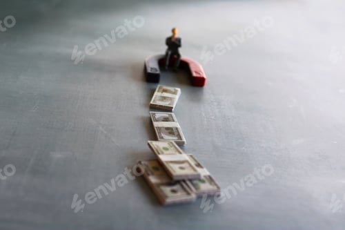 Preview: Selective focus image of miniature businessman attracts money using magnet