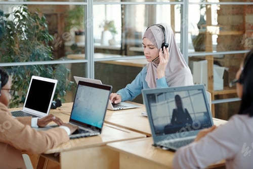 Preview: Muslim female operator in hijab and headset consulting clients online