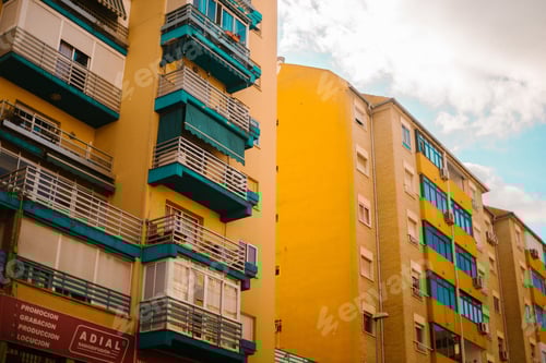 Preview: Cloudy sky over yellow apartment building
