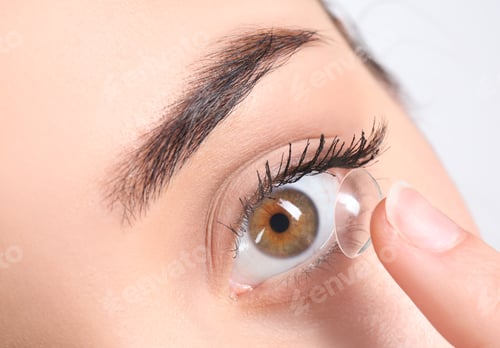 Preview: Young woman putting contact lens in her eye, closeup