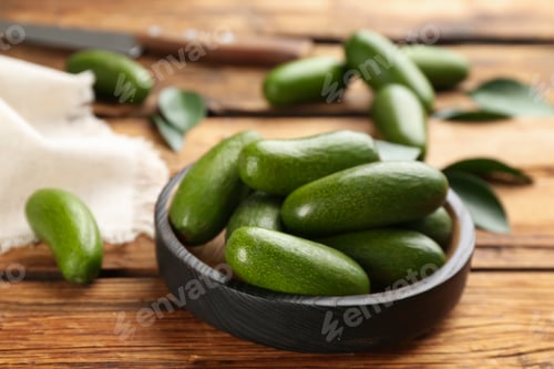 Preview: Fresh avocados with green leaves on wooden table, closeup