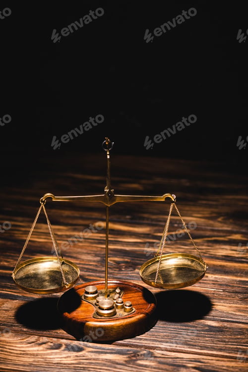 Preview: golden scales of justice on wooden table on black background