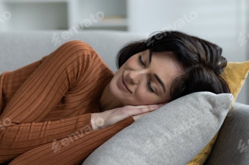 Preview: Close-up photo of a young brunette woman sleeping and resting at home on the sofa, lying on a