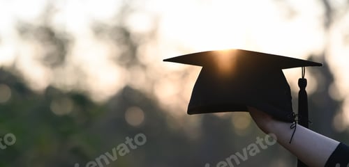 Preview: Cropped image of university student hand holding a graduation hat.